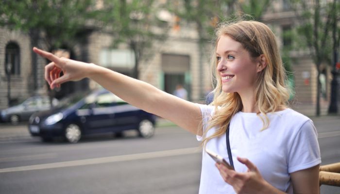 Mujer en la calle señalando un negocio que aparece en Google Maps.