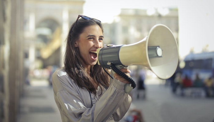 Imagen que muestra a una mujer sosteniendo un megáfono que representa cómo promocionar una tienda online.