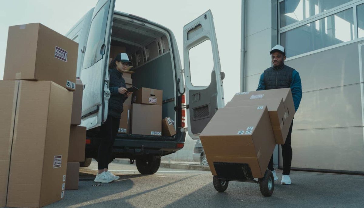 Imagem mostra equipe transportando caixas de produto em um carro, ilustrando texto sobre cubagem