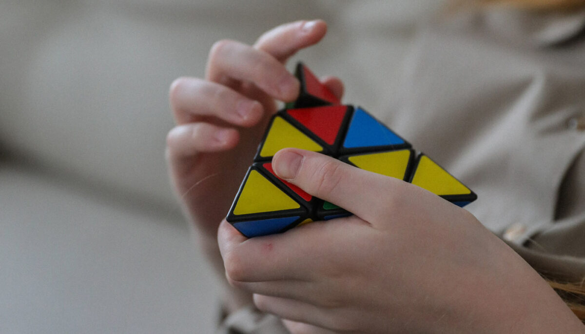 Triángulo de colores en las manos de una persona que representan la pirámide de Maslow.