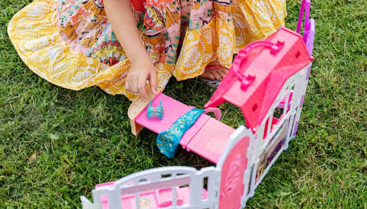 imagem de menina brincando com uma casinha de bonecas, representando um dos brinquedos mais vendidos