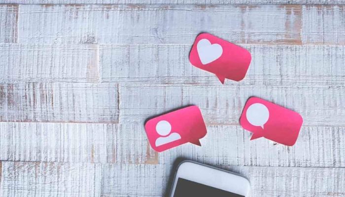 Un smartphone y carteles que representan likes, comentarios y seguidores para explicar cómo generar más engagement en Instagram.