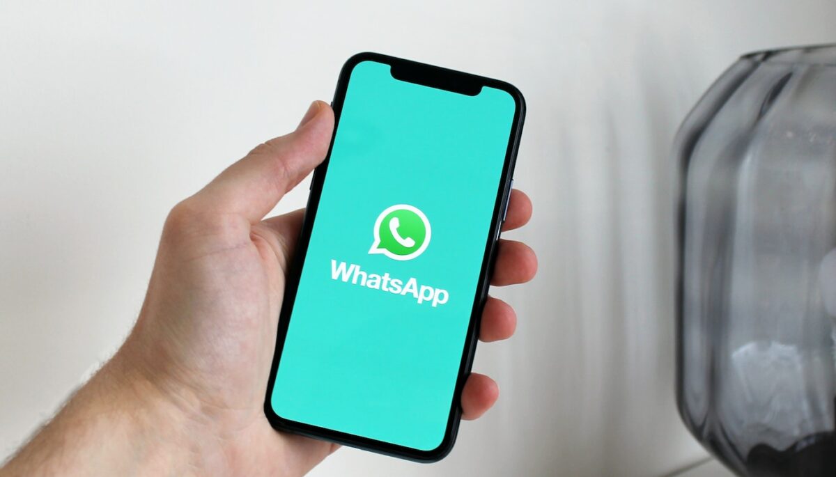 Persona sosteniendo un celular con el logo de WhatsApp, como si fuera alguien que usa la lista de difusión de WhatsApp.