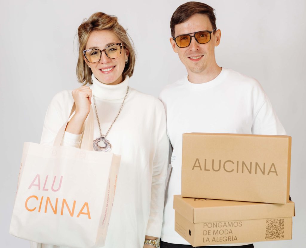 Los fundadores de Alucinna posan con bolsas y cajas con el nombre de su tienda.