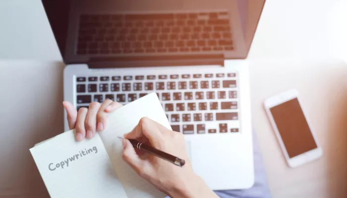 Guía de copywriting: escribe textos persuasivos para vender más Emprendedor haciendo copywriting en un cuaderno y en su computadora.