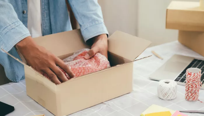 Diferencias entre empaque y embalaje: tipos y ejemplos Persona acomodando el empaque y embalaje del producto antes de enviarlo.
