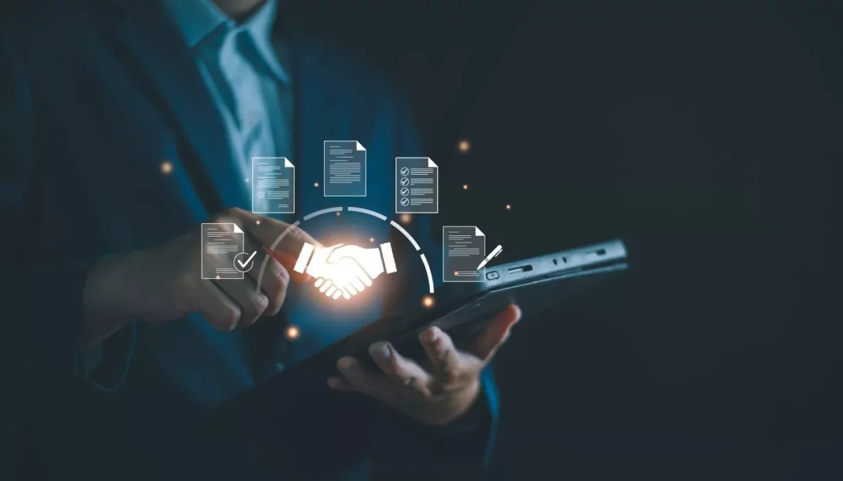 O que é gestão de fornecedores e como fazer com eficiência? Profissional fazendo a gestão de fornecedores através de um tablet com ícones de contratos e um aperto de mão simbolizando a parceria.