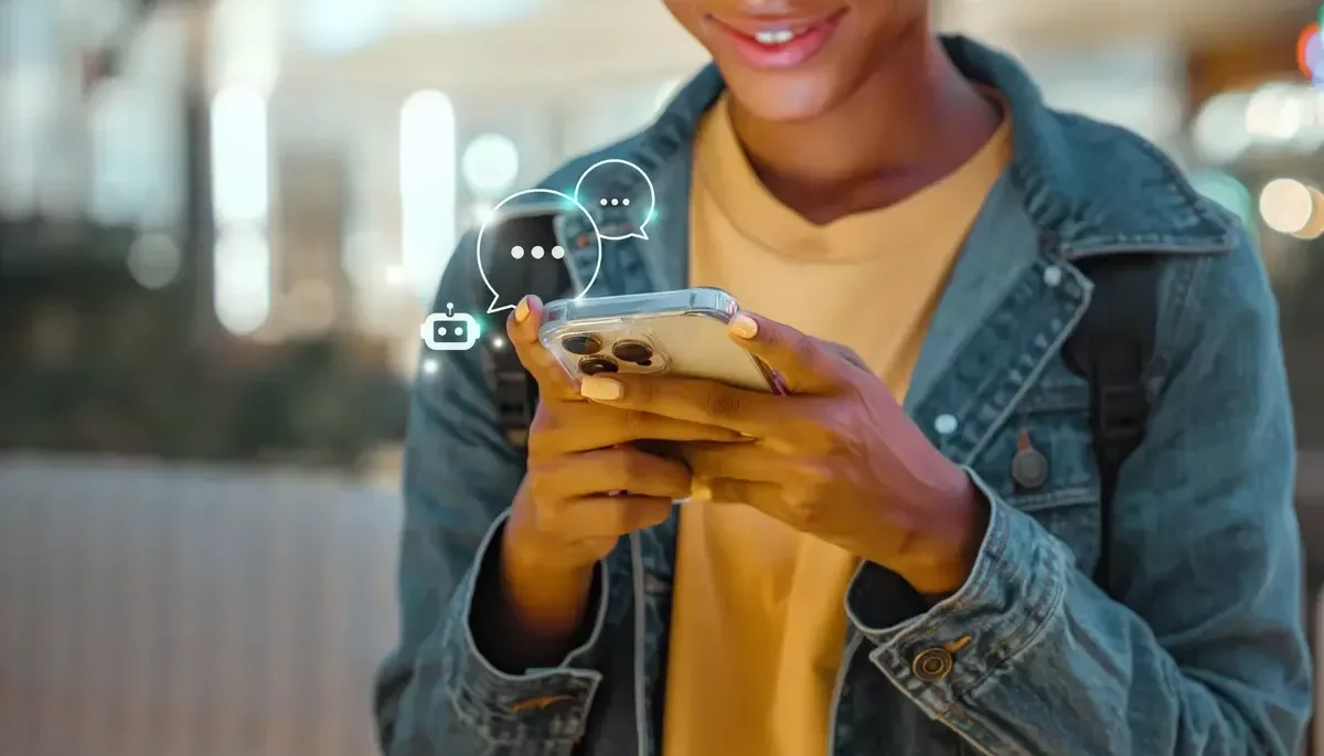 Como fazer a automação do WhatsApp para vender mais? Pessoa segurando um celular enquanto ícones e símbolos de mensagens sendo enviadas aparecem, representando como fazer automação de WhatsApp.