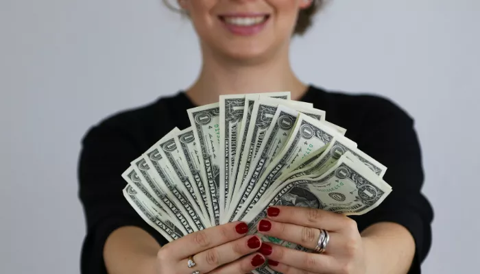 Cómo conseguir dinero rápido: 21 maneras de lograrlo Persona mostrando efectivo tras aprender cómo generar dinero rápido.