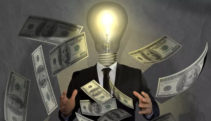 ¿Cómo generar ingresos extra en Chile? 11 ideas que sí funcionan Foco brillando rodeado de dinero, para hacer referencia de cómo generar ingresos extra en Chile.