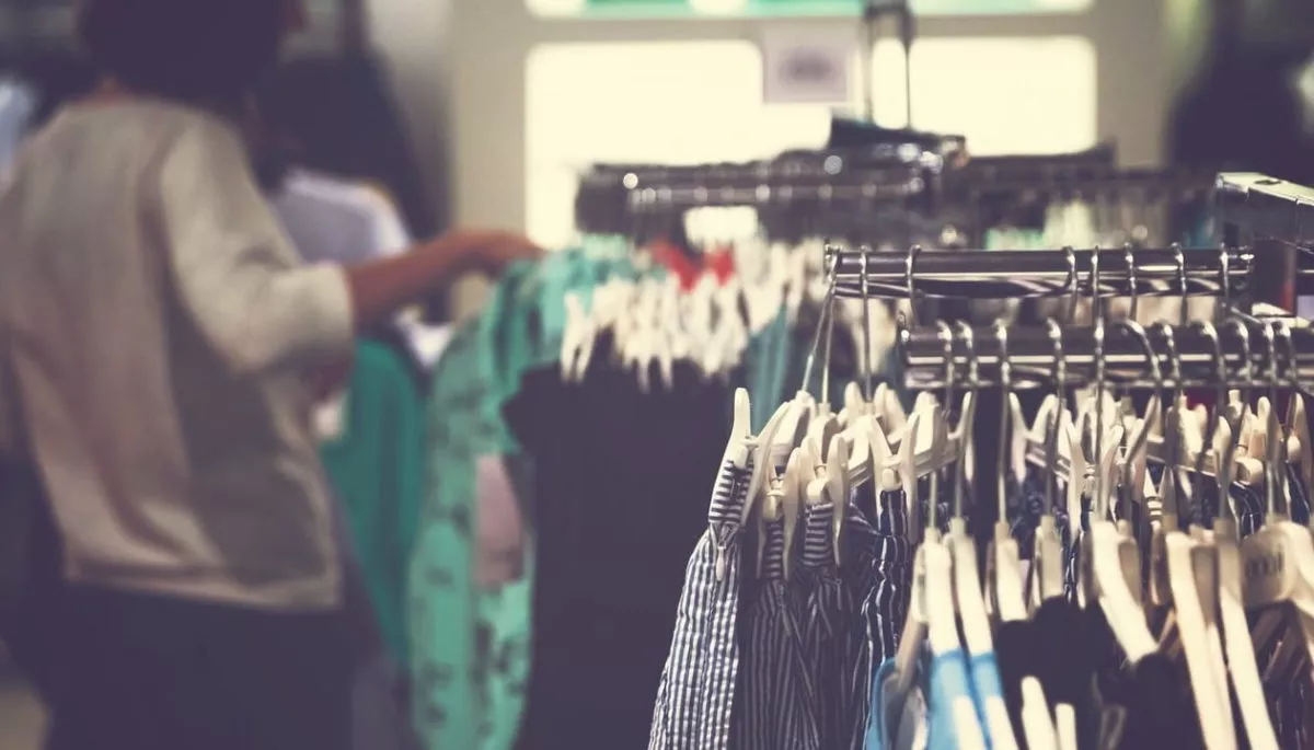 Racks de ropa con una mujer de perfil agarrando una prenda