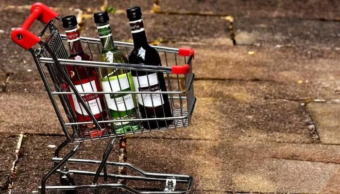 Carrito de compras con 3 botellas de vino que representan parte del proceso para vender alcohol por internet.
